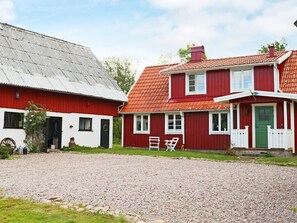 A traditional red and white house with a gravel driveway and a green door. - 8 Person Holiday Home in Hishult (Hishult)