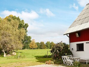 A red barn with a white exterior, surrounded by a grassy field and trees. - 8 Person Holiday Home in Hishult (Hishult)