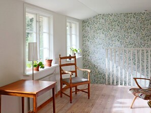 A room with a wooden chair, a small table, and a window with potted plants. - 8 Person Holiday Home in Hishult (Hishult)