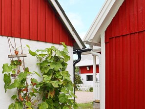 A red building with a white wall and a vine climbing up the side. - 8 Person Holiday Home in Hishult (Hishult)