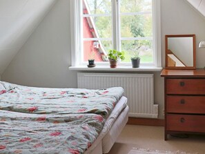 A bedroom with a bed, a dresser, a mirror, and a window with plants. - 8 Person Holiday Home in Hishult (Hishult)