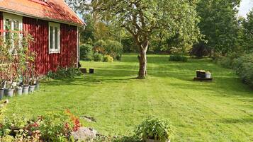A red wooden house with a well-maintained lawn and garden.