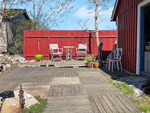 A wooden deck with outdoor furniture, a red fence, and potted plants. - 2 Person Holiday Home in Brosarp (Brosarp)