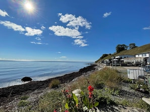 A coastal view with a clear sky, a rocky shoreline, and a building with outdoor seating. - 2 Person Holiday Home in Brosarp (Brosarp)