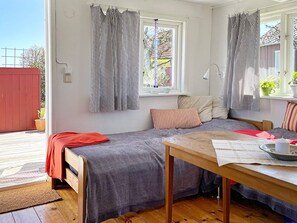 A cozy room with two beds, a wooden table, and a window with striped curtains. - 2 Person Holiday Home in Brosarp (Brosarp)
