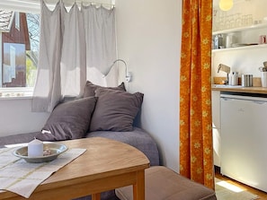A cozy room with a bed, a small table with a candle, and a kitchen area with a dishwasher. - 2 Person Holiday Home in Brosarp (Brosarp)