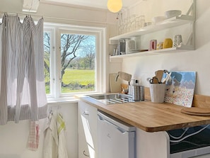 A kitchen with a window, a sink, a stove, and shelves with kitchenware. - 2 Person Holiday Home in Brosarp (Brosarp)