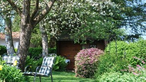 A garden with a wooden cabin, a lawn, and two metal chairs. - Haus Jorg Sosna Modern Retreat (Bad Bayersoien)
