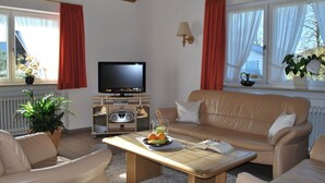 A living room with a television, sofa, coffee table, and potted plants. - Haus Jorg Sosna Modern Retreat (Bad Bayersoien)