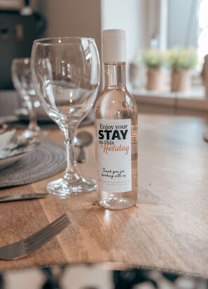 Une bouteille avec une étiquette sur laquelle on peut lire « Profitez de votre séjour pendant ces vacances » et un verre posé sur une table en bois.