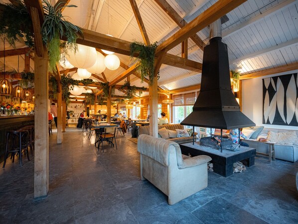 Relax in a cozy atmosphere with sofas and a bar area, surrounded by hanging plants and pendant lights.