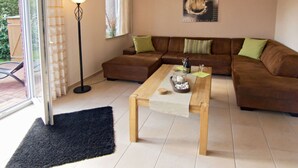 A living room with a brown sofa, a wooden coffee table, and a floor lamp. - Lovely Apartment in Hage (Berumbur)