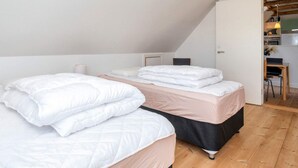 A bedroom with two beds, a wooden floor, and a kitchenette in the adjacent room. - 4 Star Holiday Home in Thisted (Thisted)