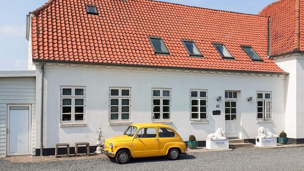 A white building with a red-tiled roof, numbered 43, and a yellow car parked in front. - 4 Star Holiday Home in Thisted (Thisted)