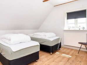 Ett sovrum med två sängar, ett fönster med persienner och ett element.