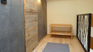 Ein Zimmer mit schrägem Dach, Holzwandverkleidung, einer Bank und einem Oberlicht.