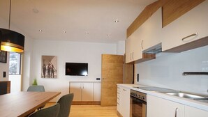Eine moderne Küche mit weißen Schränken, einem eingebauten Backofen und einem großen Fenster.