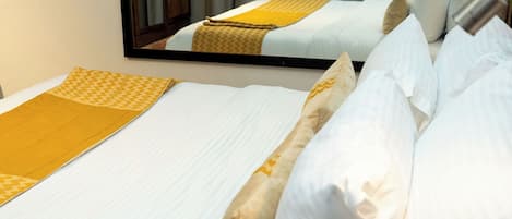 A hotel room with two beds, each with white linens and a yellow patterned bedspread.