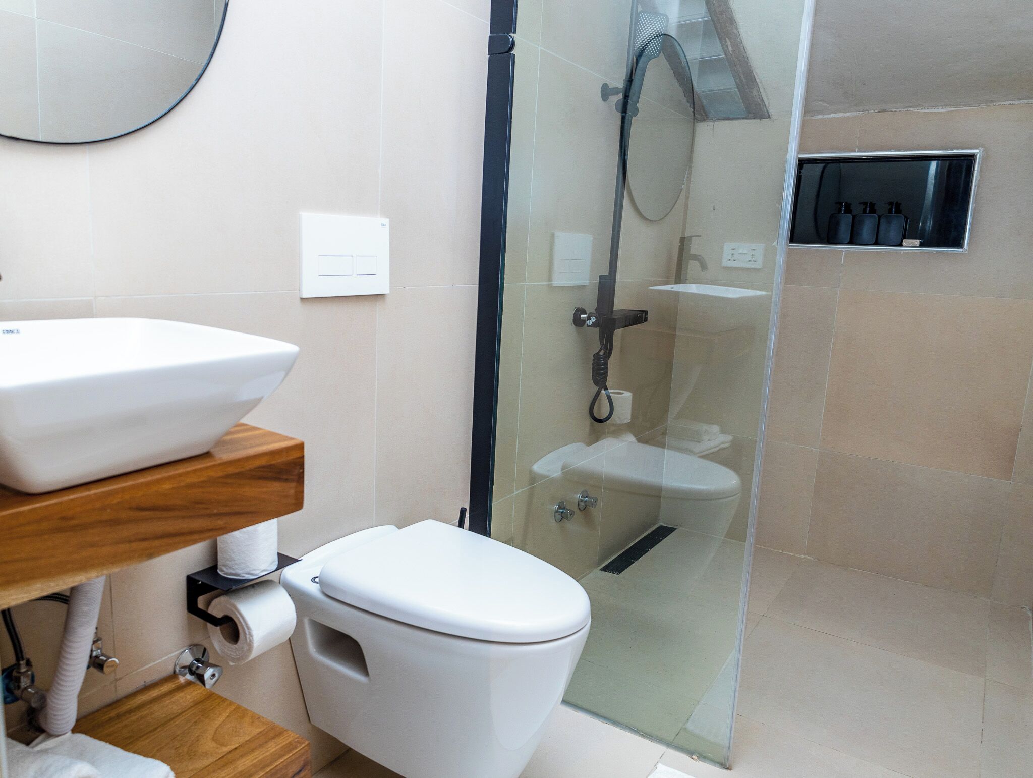 Une salle de bain moderne avec une douche à parois de verre, des toilettes blanches et un meuble-lavabo en bois avec un évier.