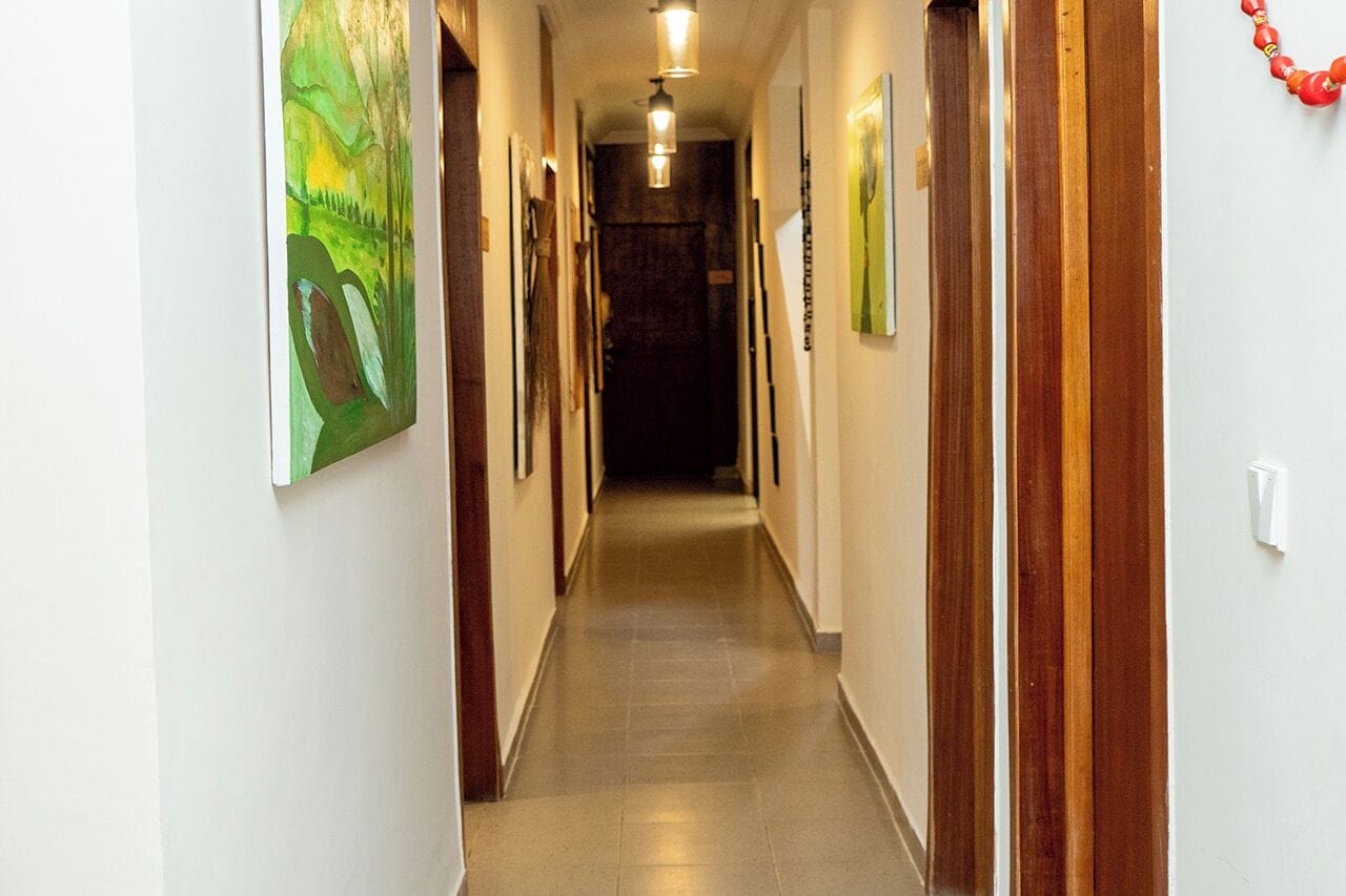 A hallway with wooden doors, framed artwork on the walls, and a light fixture on the ceiling.