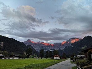 Paisaje rural con una cordillera al fondo, una carretera despejada y varias casas.