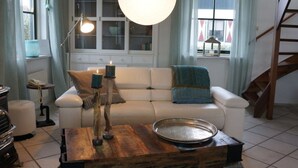 Un salon avec un canapé blanc, une table basse en bois et un luminaire suspendu.