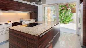 Una cocina moderna con una isla central, armarios de madera oscura y un amplio ventanal con vistas a un jardín.
