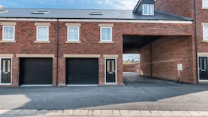 A multi-story brick building with a garage entrance and two closed garage doors. - Bay Retreat Apartment in Skinningrove (Saltburn-by-the-Sea)