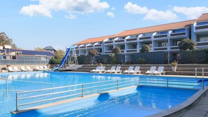 A swimming pool with a slide, lounge chairs, and a building with a red roof in the background. - 6 Person Holiday Home on a Holiday Park in Faaborg (Faaborg)