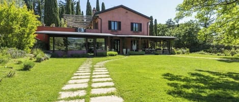 A modern house with a covered patio, a well-maintained lawn, and a stone pathway leading to the entrance.