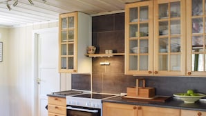 A kitchen with wooden cabinets, a stove, and a tiled backsplash. - 4 Star Holiday Home in Halden (Halden)
