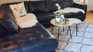 A black leather sofa with a fluffy white throw pillow and a small side table with a vase of flowers. - 4 Star Holiday Home in Halden (Halden)