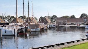 A marina with docked boats and a grassy area. - Villa in Friesland With Waterfront Jetty (Idskenhuizen)