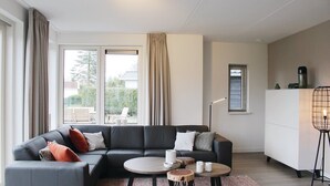 A modern living room with a sectional sofa, round coffee tables, and a standing floor lamp. - Villa in Friesland With Waterfront Jetty (Idskenhuizen)