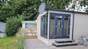 A modern house with a satellite dish, a wooden planter, and a paved patio. - Chalet With Dishwasher in a Park (Lathum)