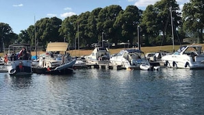 A marina with various boats docked, surrounded by trees and a clear sky. - Chalet With Dishwasher in a Park (Lathum)
