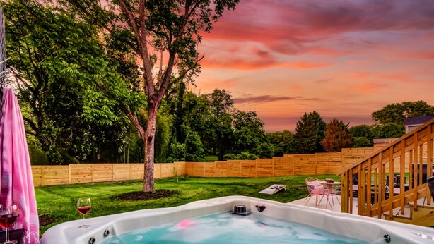 Ein Whirlpool in einem Garten mit einer Holzterrasse, einem Baum und einem Holzzaun.