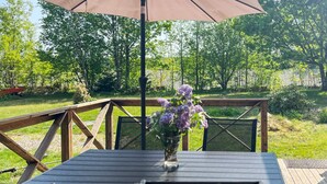 A wooden deck with a table and chairs, a metal railing, and a flower vase. - 4 Star Holiday Home in Annerstad (Annerstad)