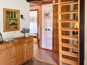 A wooden interior with a kitchen area, a mirror, a vase with flowers, and a wooden shelving unit. - 4 Star Holiday Home in Annerstad (Annerstad)