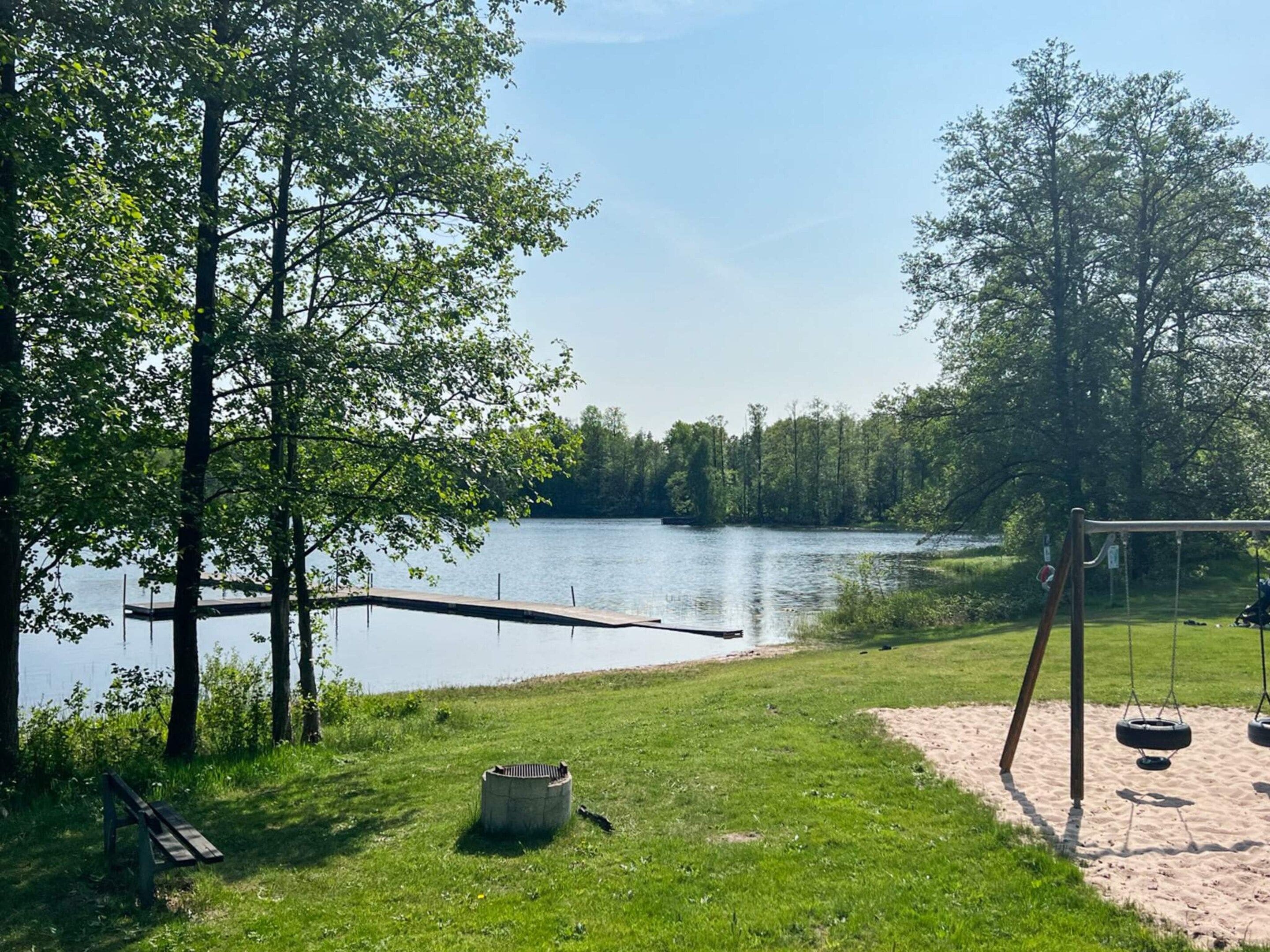 Un parc a la vora d'un llac amb un tobogan, una banca i una xemeneia.