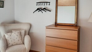 A room with a wooden dresser, a chair with floral cushions, and a wall-mounted coat rack. - 4 Star Holiday Home in Annerstad (Annerstad)