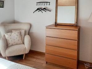 A room with a wooden dresser, a chair with floral cushions, and a wall-mounted coat rack. - 4 Star Holiday Home in Annerstad (Annerstad)