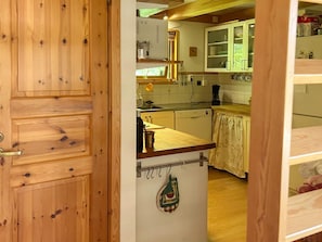 A wooden door leading into a kitchen with white cabinets, a sink, and a countertop. - 4 Star Holiday Home in Annerstad (Annerstad)