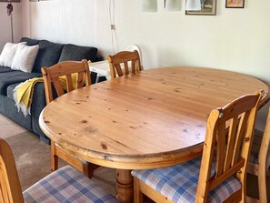 A dining area with a wooden round table surrounded by chairs with plaid cushions. - 4 Star Holiday Home in Annerstad (Annerstad)