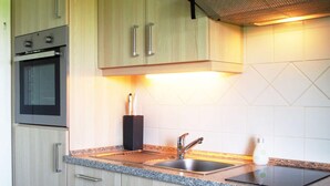 A modern kitchen with wooden cabinets, a built-in oven, a granite countertop, and a stainless steel sink. - Holiday Apartment Lugworm (Ockholm)