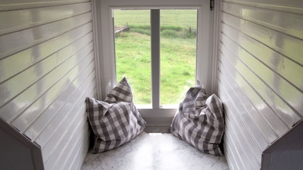 A room with a window, two checkered pillows, and a view of a grassy field. - Holiday Apartment Lugworm (Ockholm)