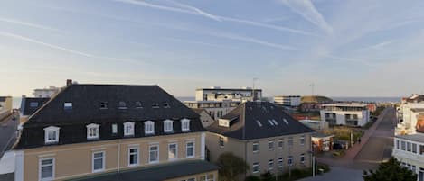 Un quartier résidentiel où se côtoient des bâtiments à l’architecture moderne et traditionnelle, avec notamment un immeuble imposant doté d’un toit en pente et un bâtiment plus petit avec un toit plat.