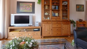 Ein Wohnzimmer mit einem Holzschrank, einem Fernseher und einem gerahmten Gemälde an der Wand.