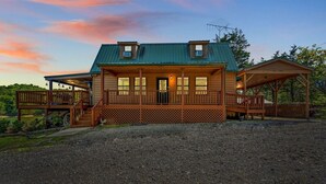 A two-story log cabin with a porch, a covered outdoor seating area, and a gravel driveway. - Lakefront Mtn Retreat w Private Boat Dock & Launch (Sevierville)