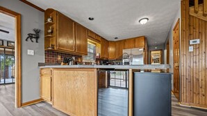 A kitchen with wooden cabinets, a stainless steel refrigerator, and a dishwasher. - Lakefront Mtn Retreat w Private Boat Dock & Launch (Sevierville)
